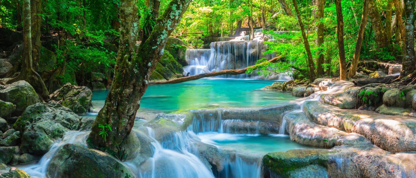 Table with white linen on a stone platform beside the waterfall pool