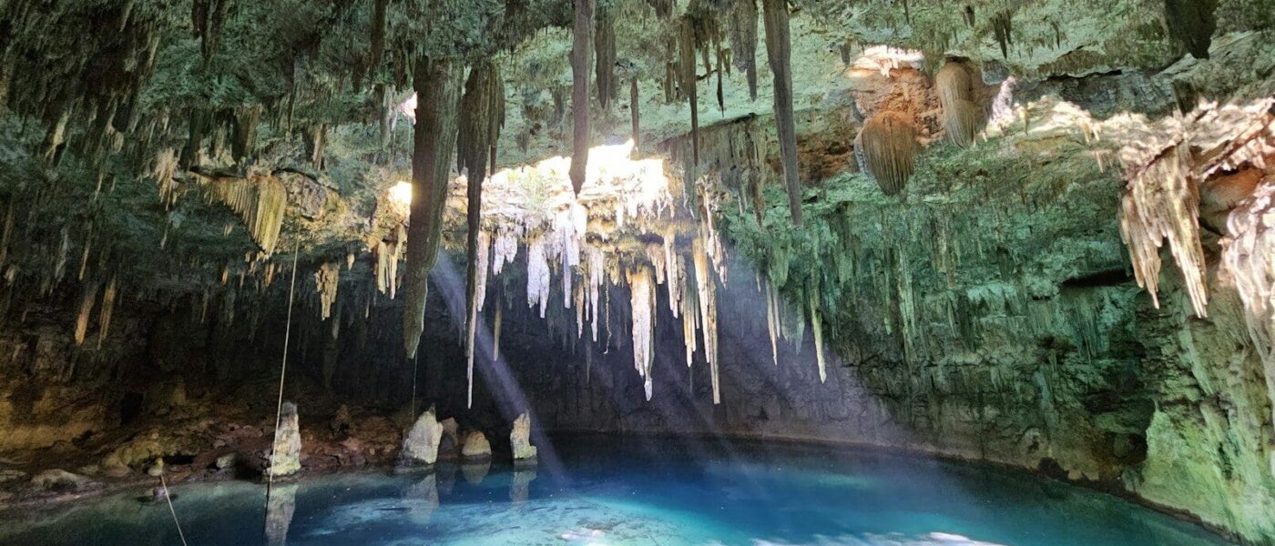 Narrow entrance of Taak Bi Ha cave cenote casting light onto the water