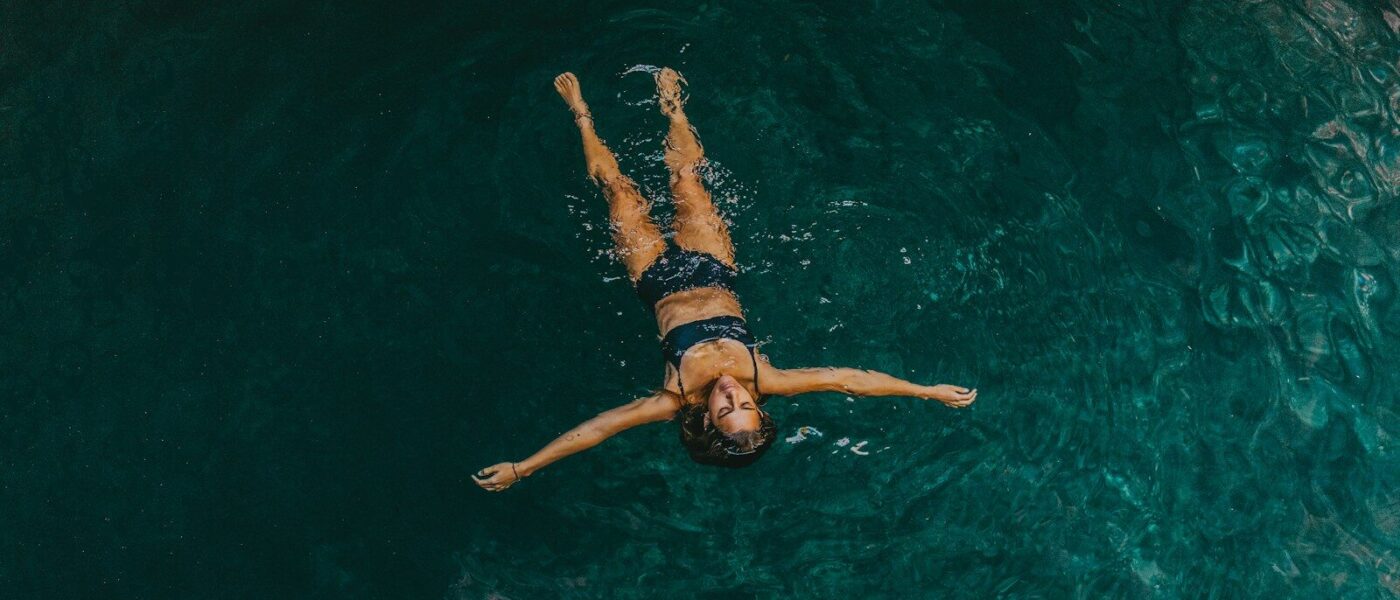 Guide waiting at the edge of a quiet cenote while guests swim