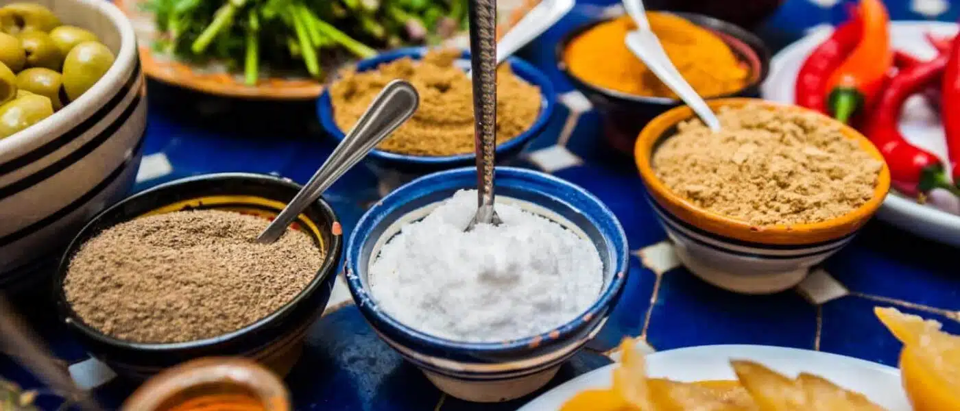 Chef adjusting spice quantities with a guest in a riad kitchen