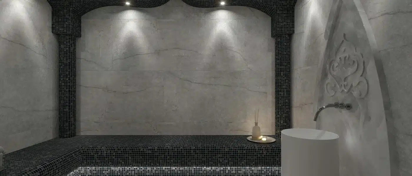 Practitioner pouring water over a guest on heated stone