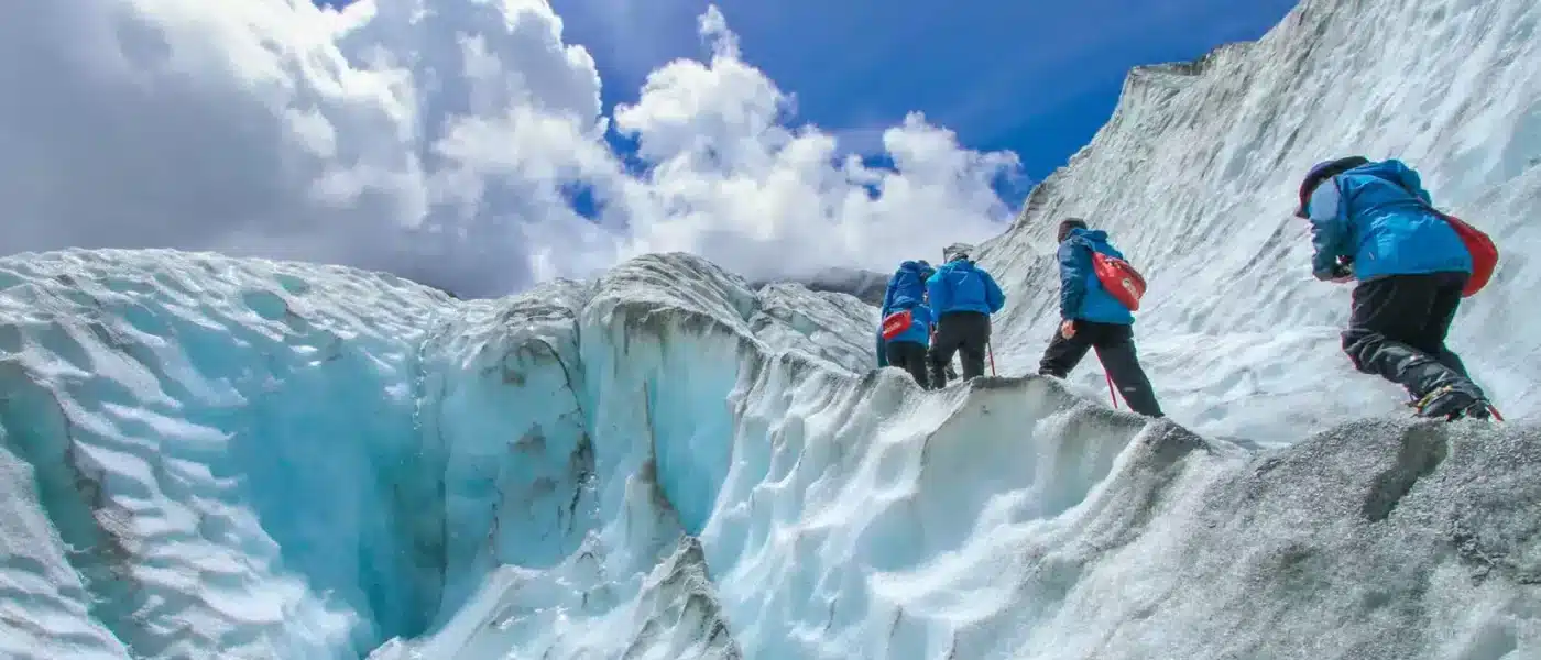 Guide and two hikers alone on a wide expanse of glacier ice