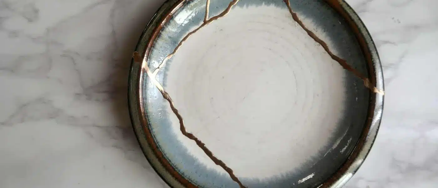 Broken ceramic fragments laid out beside urushi lacquer and gold powder