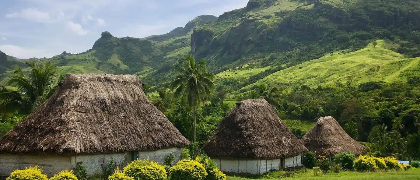 Guests in modest dress being welcomed into a Fijian village