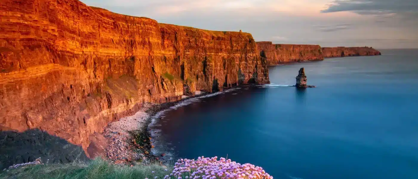 Picnic blanket and wicker basket on a grassy clifftop ledge