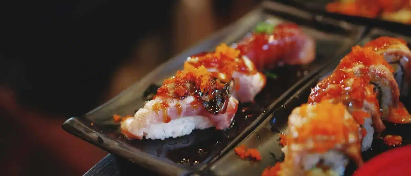 Guest tasting their own nigiri beside the chef's at the counter