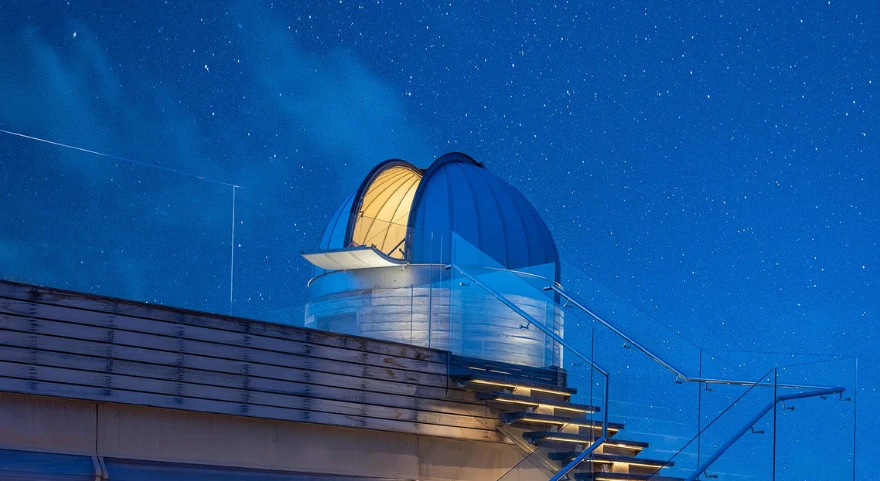 Overwater observatory dome lit up at night under a starry sky at Anantara Kihavah Maldives Villas