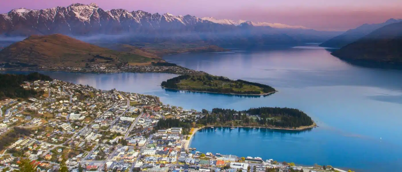Tandem skydivers in freefall above Lake Wakatipu and The Remarkables