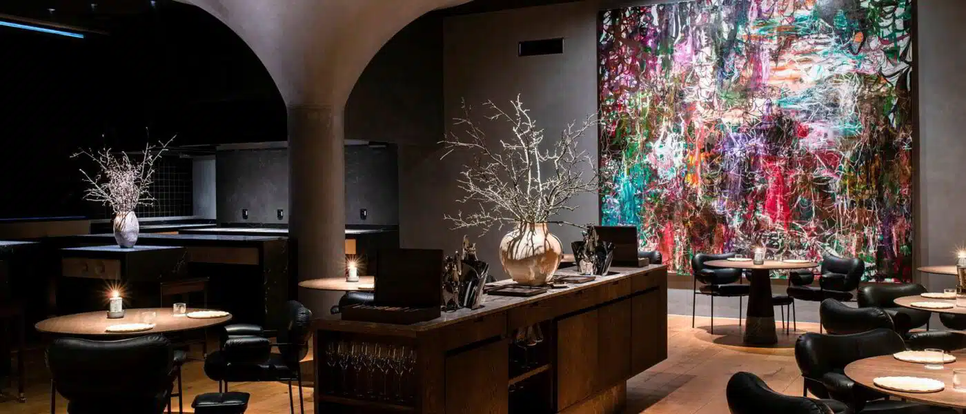 Chef bringing a course from the open kitchen to a Maaemo table