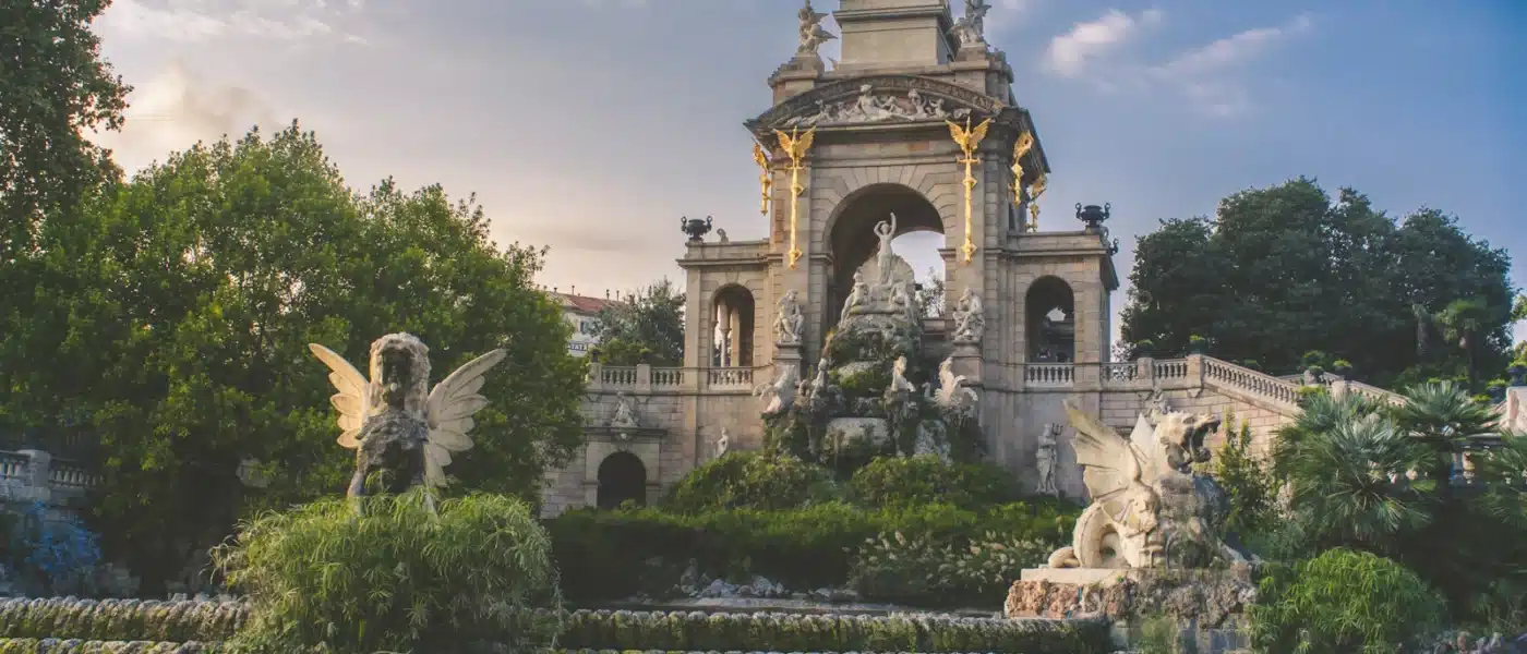 a fountain with statues and a clock tower in the background - Barcelona Ciutadella Park