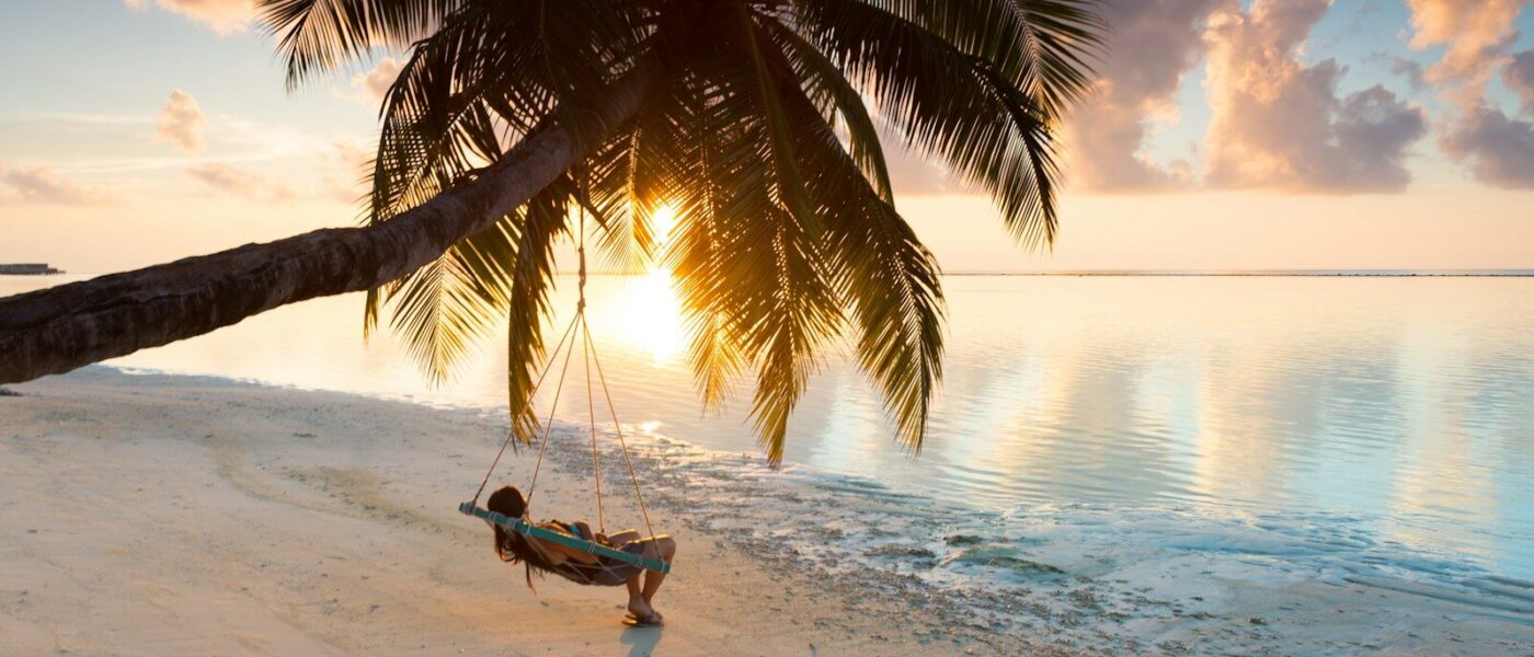 person swinging on hammock hanged on coconut tree near sea