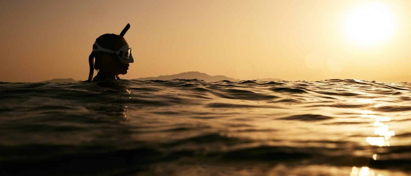 Guide briefing a snorkeler with torches at the water's edge