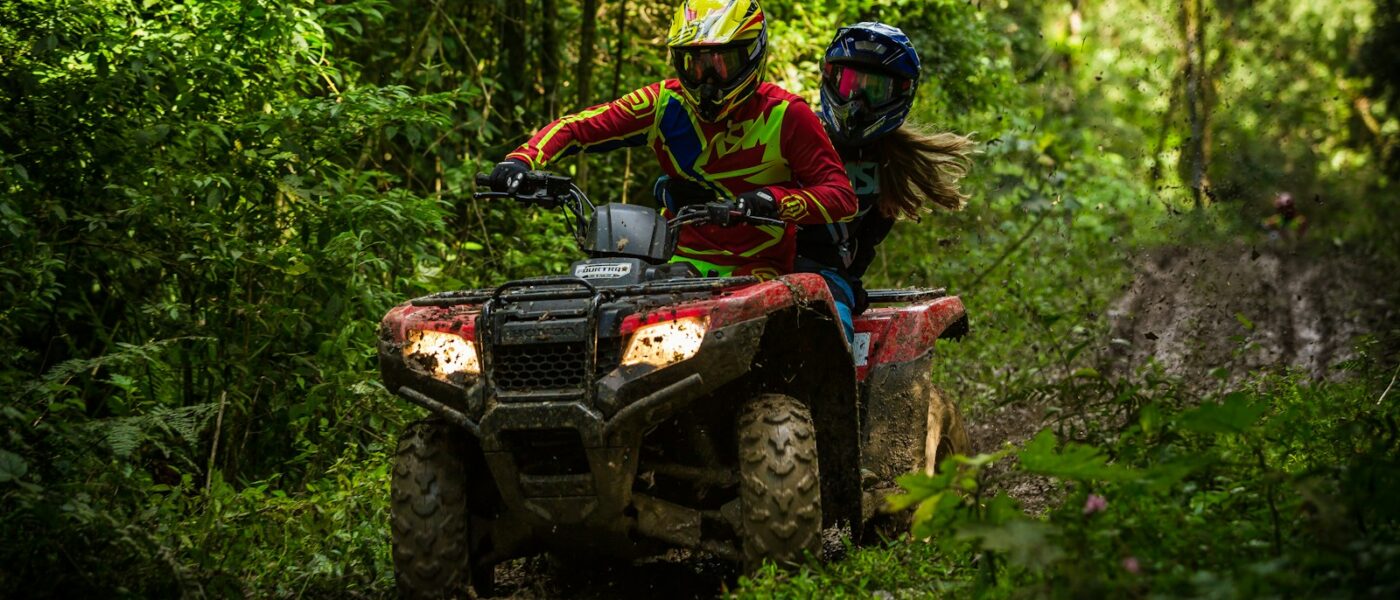 Small group of ATV riders spaced out on a jungle trail
