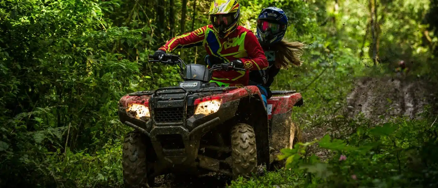 Small group of ATV riders spaced out on a jungle trail