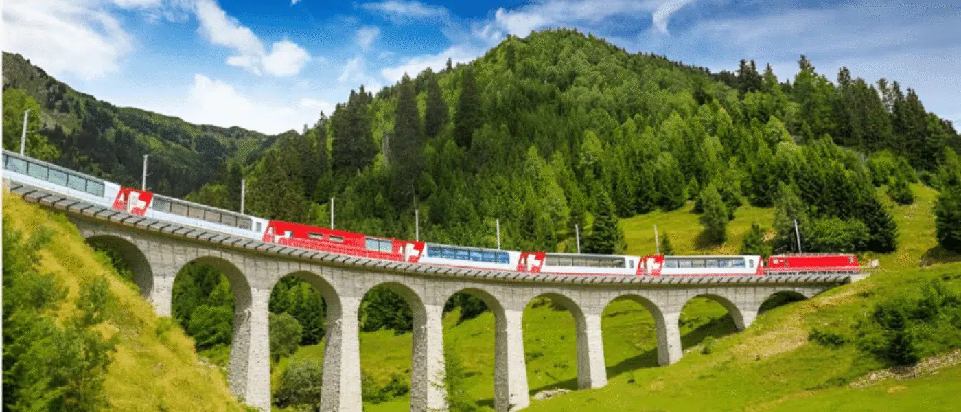 Glacier Express winding through a green valley in early summer