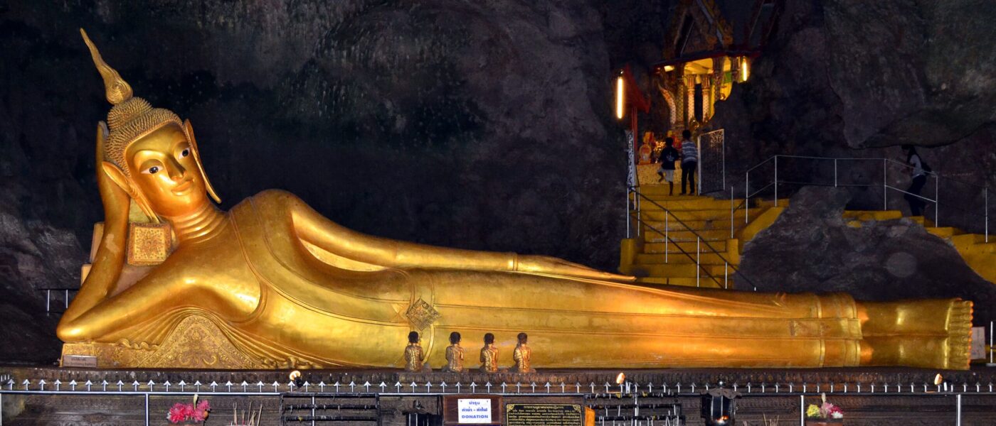 Cave entrance opening from the forested hillside at Wat Suwan Kuha